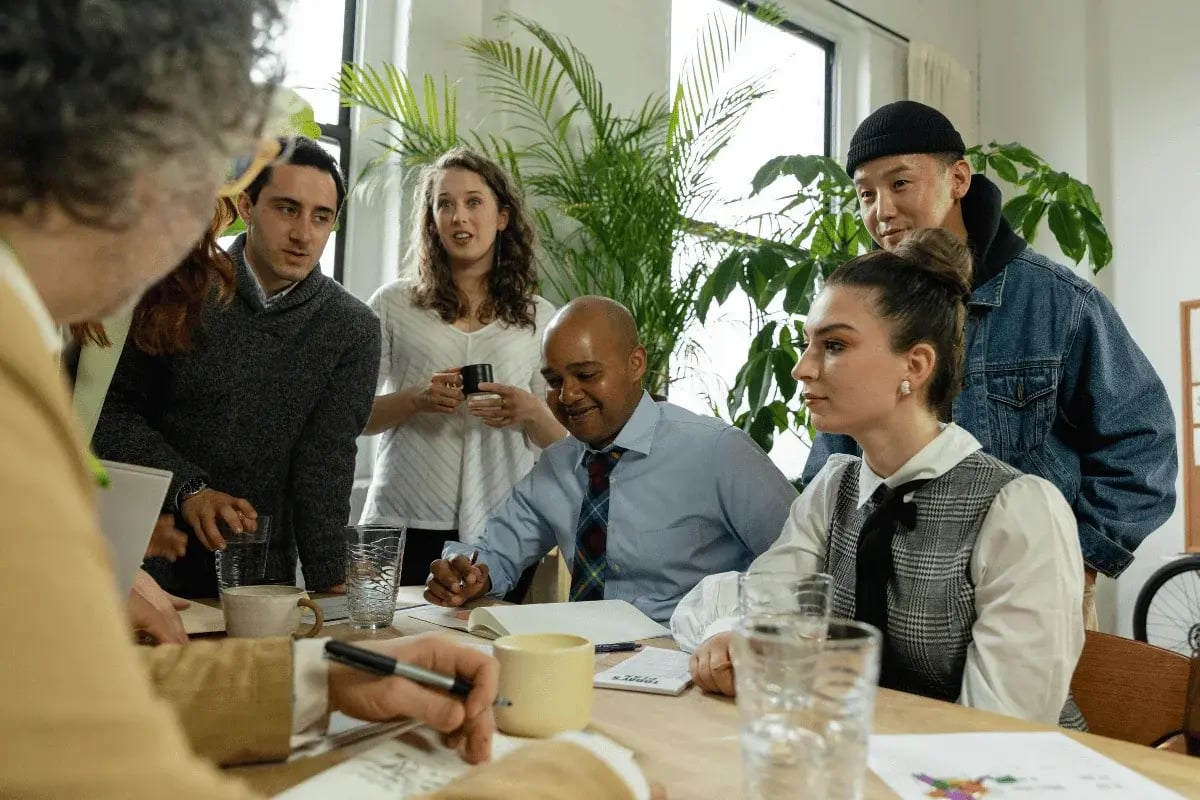 Diverse team collaborating around a table during a casual office meeting.