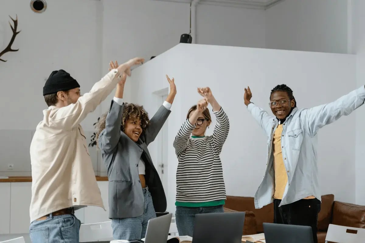 Group of young professionals cheering after achieving a business goal.
