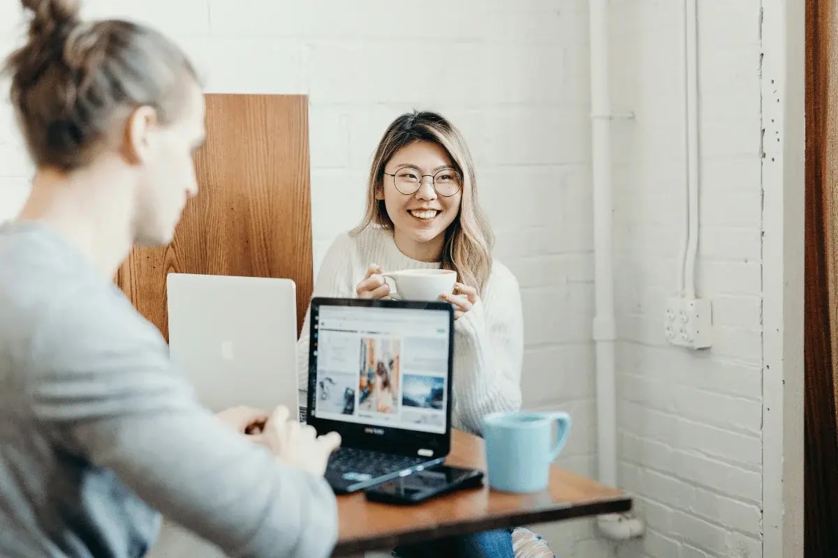 Smiling woman holding a cup during a casual work meeting.