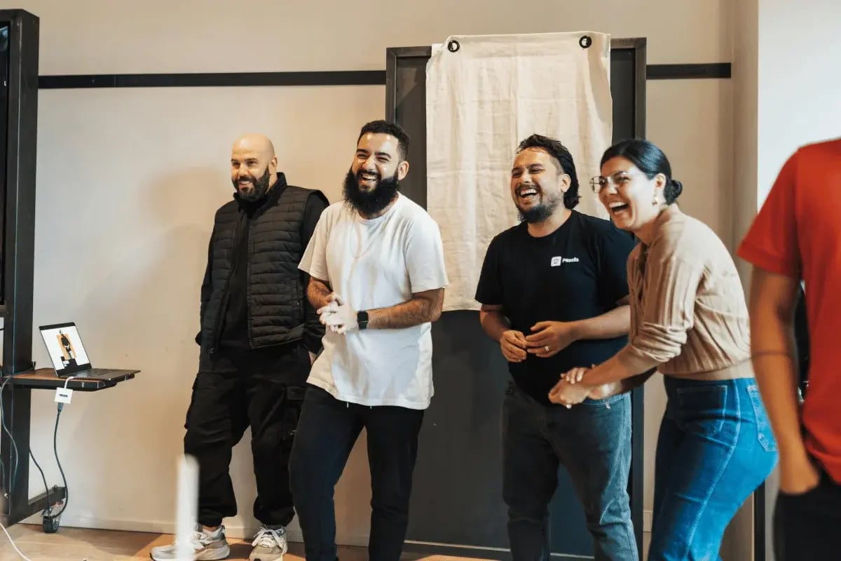 Group of coworkers laughing together in a casual office setting.
