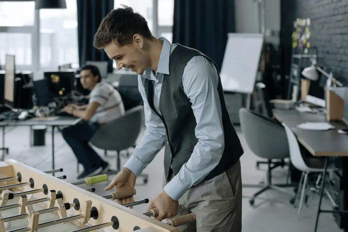 Man playing foosball in a modern office environment.