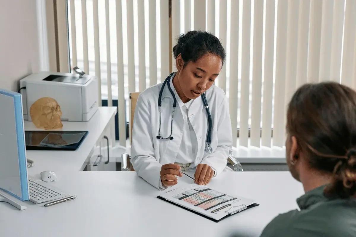 A doctor explaining a medical chart to a patient during a consultation in a clinic.