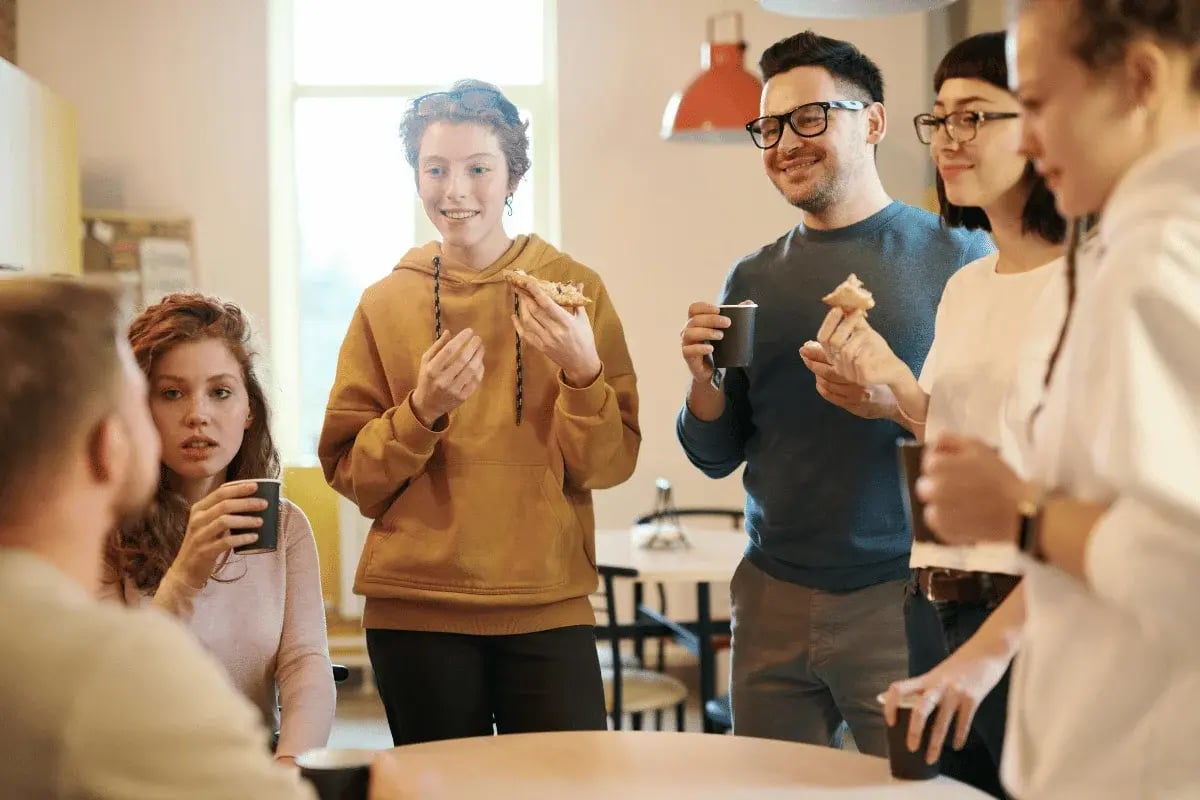 Group of colleagues enjoying coffee and snacks during office break.