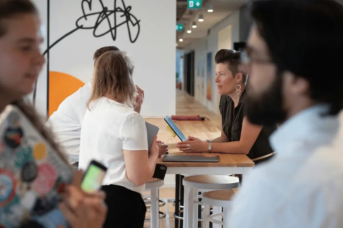 Coworkers having casual discussion at high table in office.