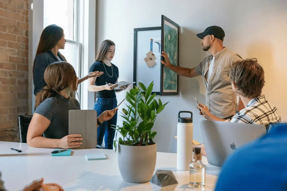A diverse team engaged in a casual meeting in an office with a brick wall.