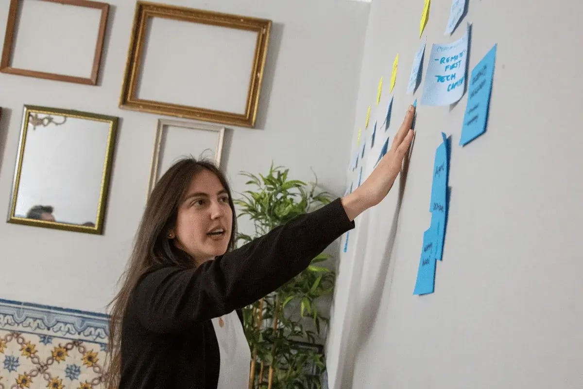 Woman presenting project ideas on sticky notes attached to wall.