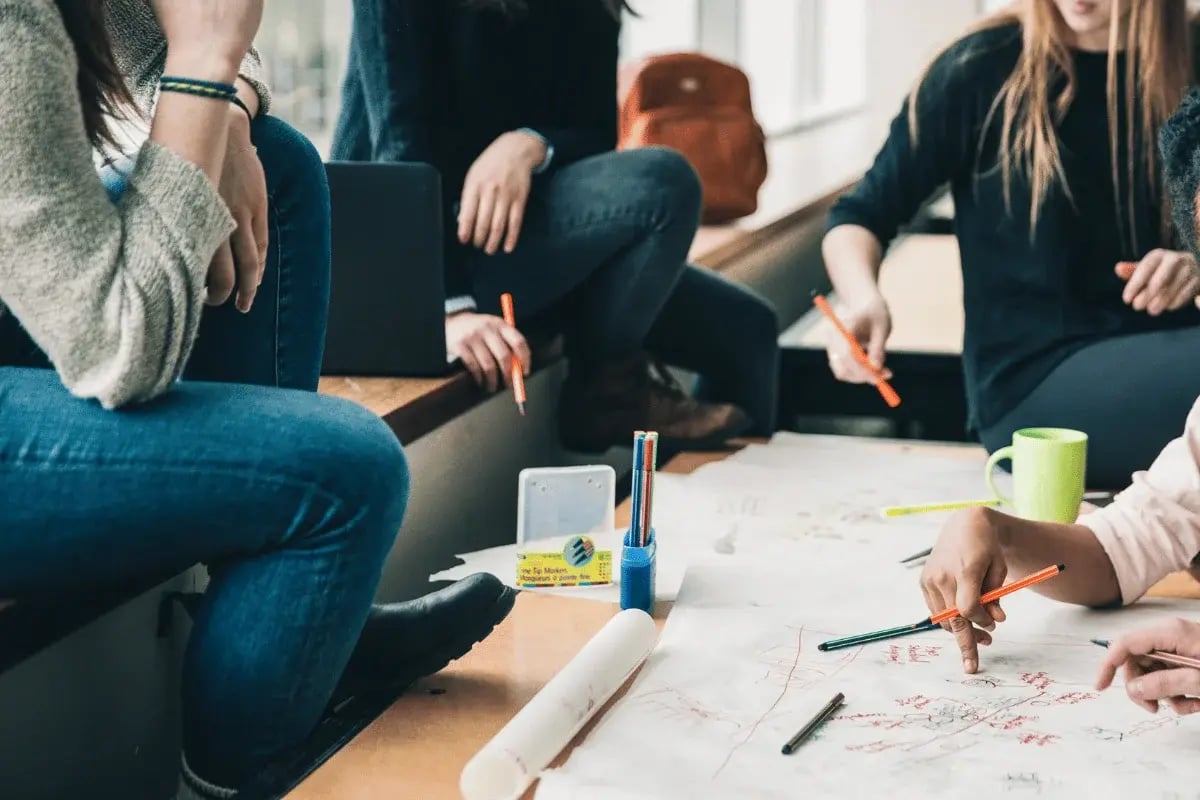 Group of people brainstorming together with papers and pens on a table.