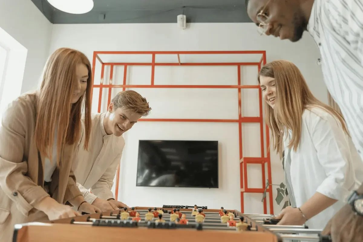 Group of coworkers playing foosball in a modern office.