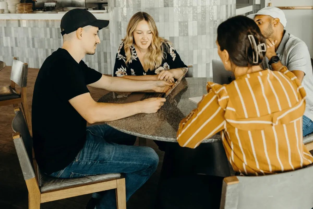 Small team meeting around a round table with laptops.