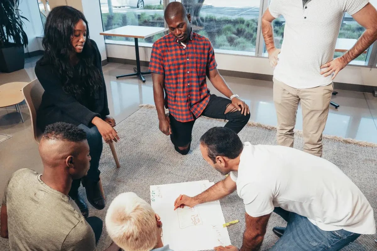 Diverse team brainstorming ideas on whiteboard during office meeting.