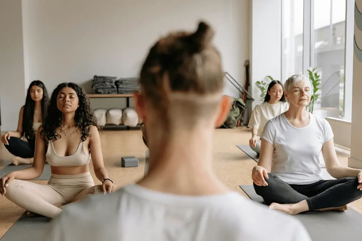 Group of people meditating in a serene yoga studio.