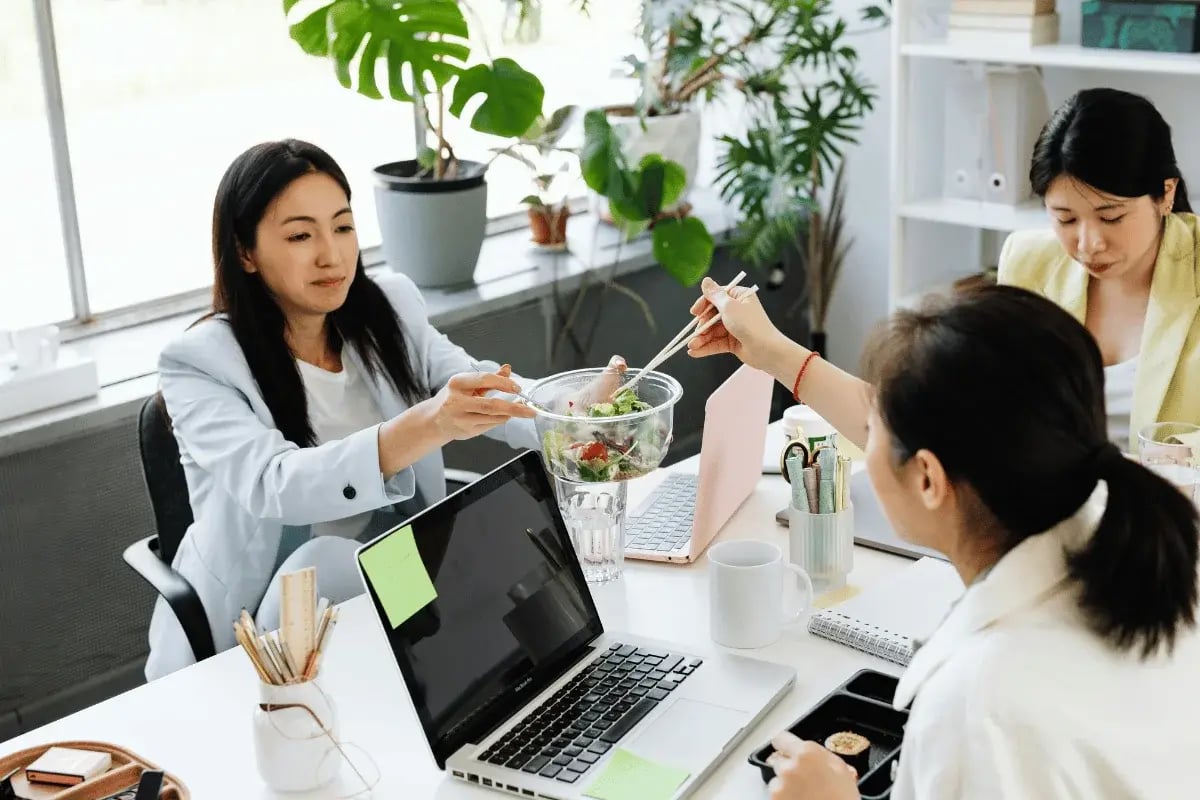 Coworkers sharing a salad during lunch break at the office.