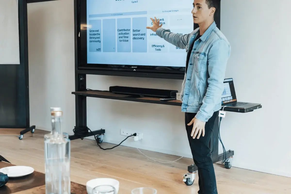 Man presenting company growth strategies to team members in a meeting room.