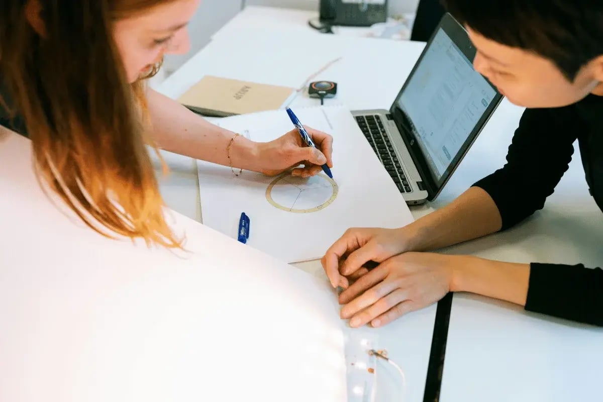 Two colleagues collaborating on a design project with sketches and laptop.