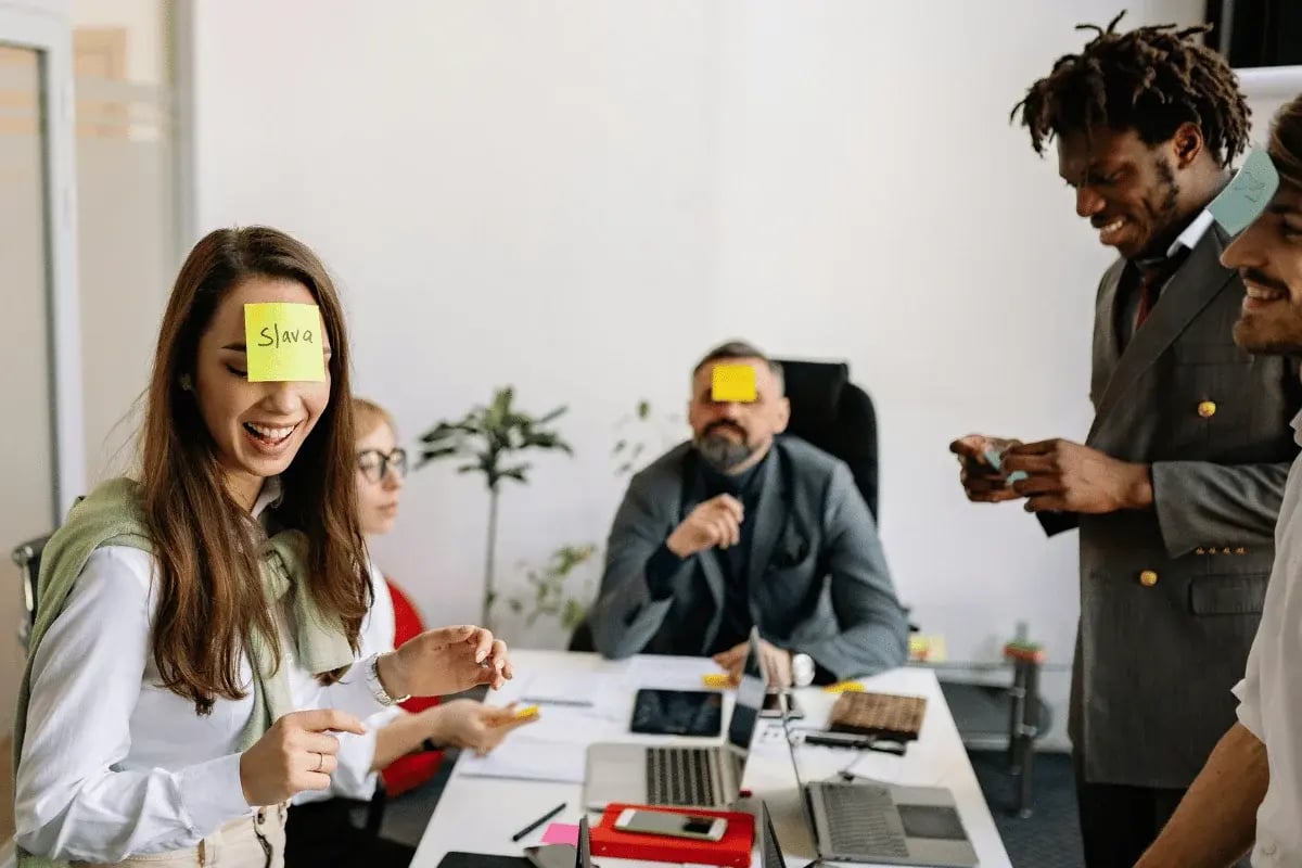 A diverse group of professionals collaborate in a modern office setting, with laptops and documents spread across a conference table.
