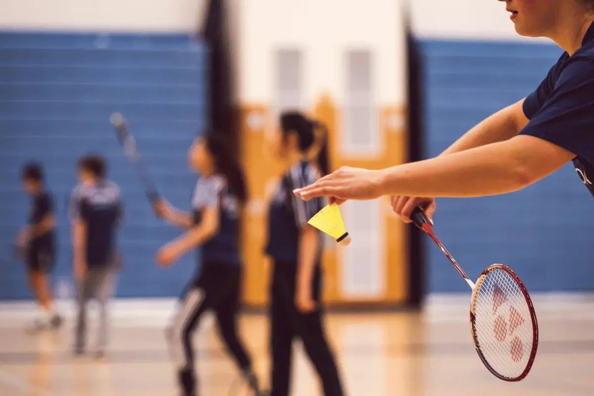 Close-up of player serving shuttlecock during badminton game indoors.