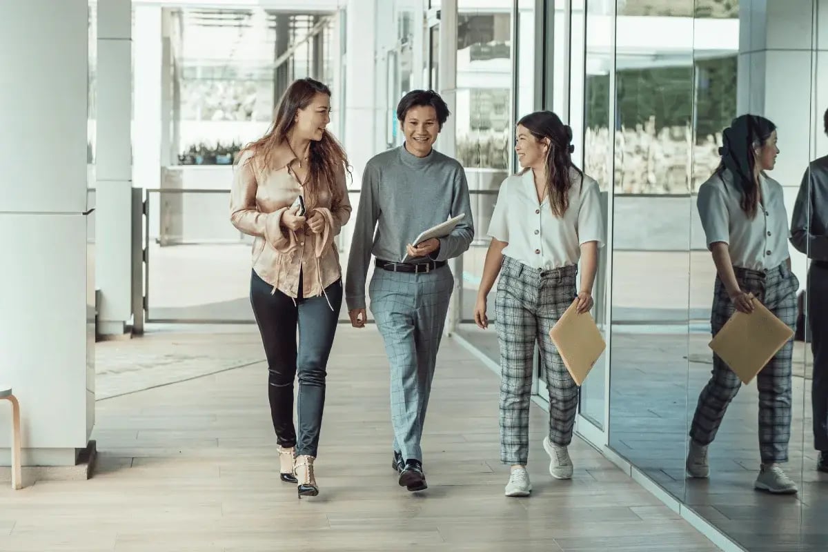 Three colleagues walking together in a modern office hallway.