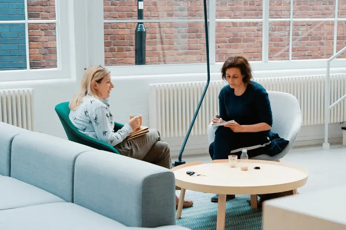 Two women having a casual business meeting in a modern office lounge.