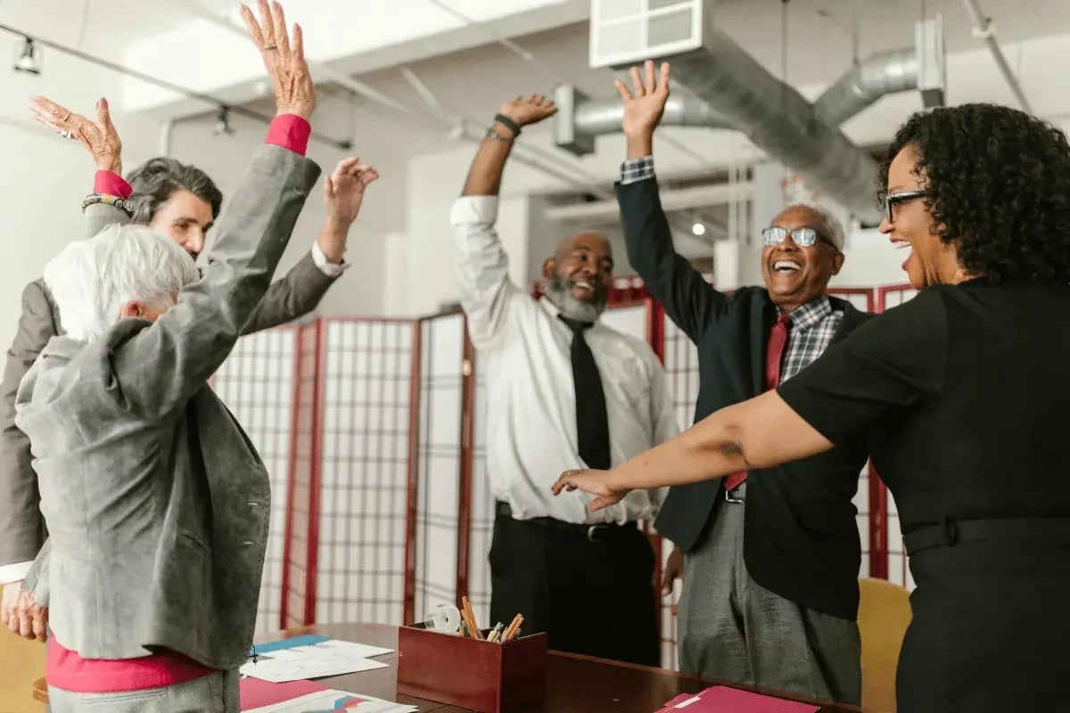 Diverse office team celebrating with raised hands.