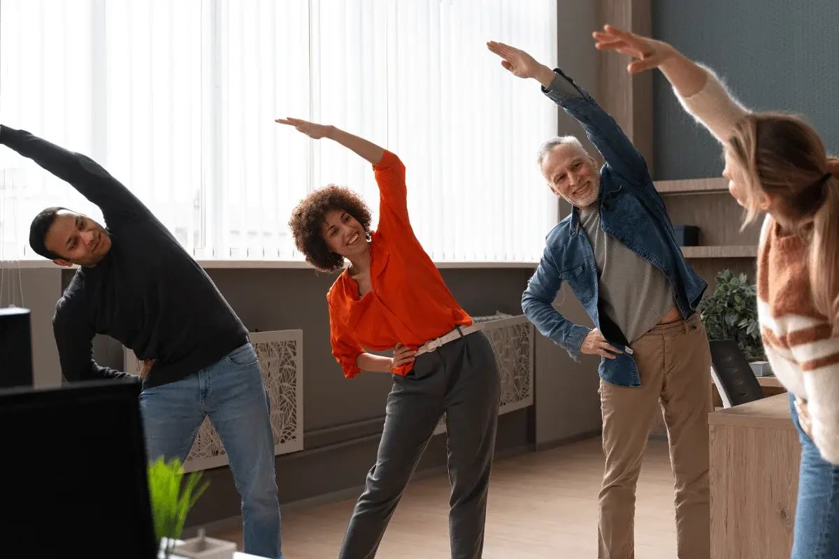 A group of people doing office stretches together in a bright, modern workspace.