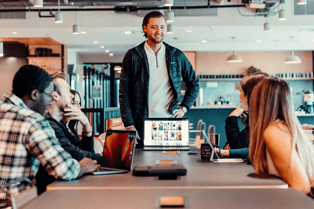 Business professional standing while colleagues listen.
