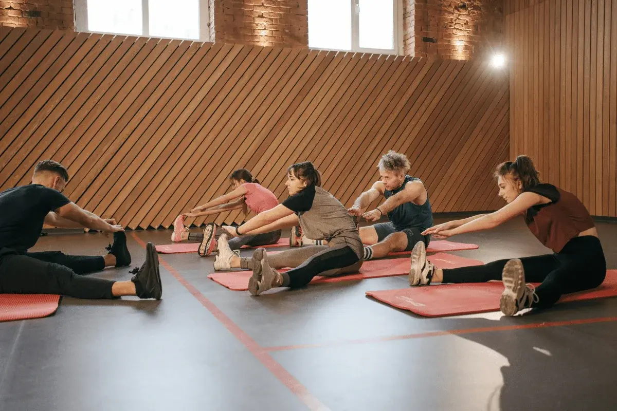 Group of people stretching on yoga mats in a fitness studio.