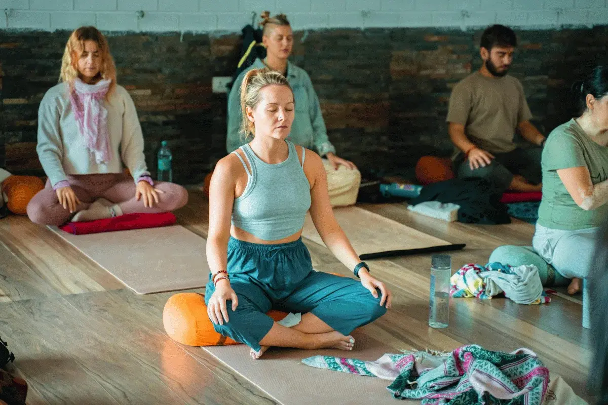 Group of people practicing mindfulness meditation in a yoga studio.